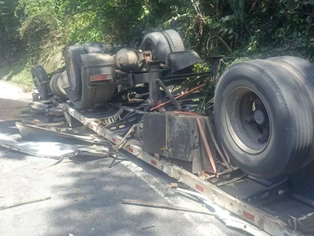 Caminhão tomba após pane no freio e motorista fica preso às ferragens